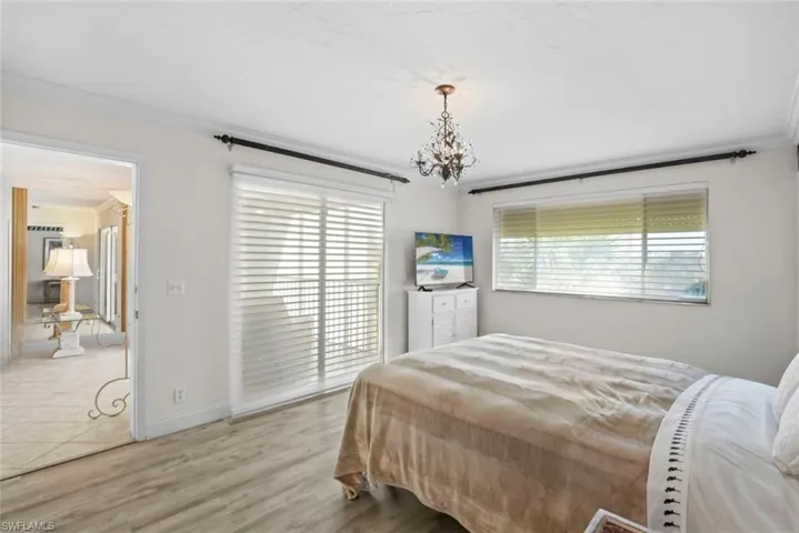 Bedroom with ornamental molding, light wood-style flooring, and suspended lighting
