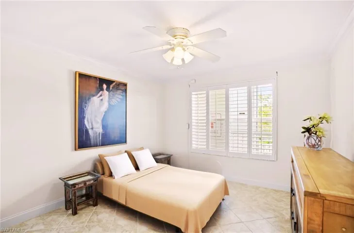 Guest-Bedroom partial staged with crown molding, a ceiling fan, and light tile patterned floors