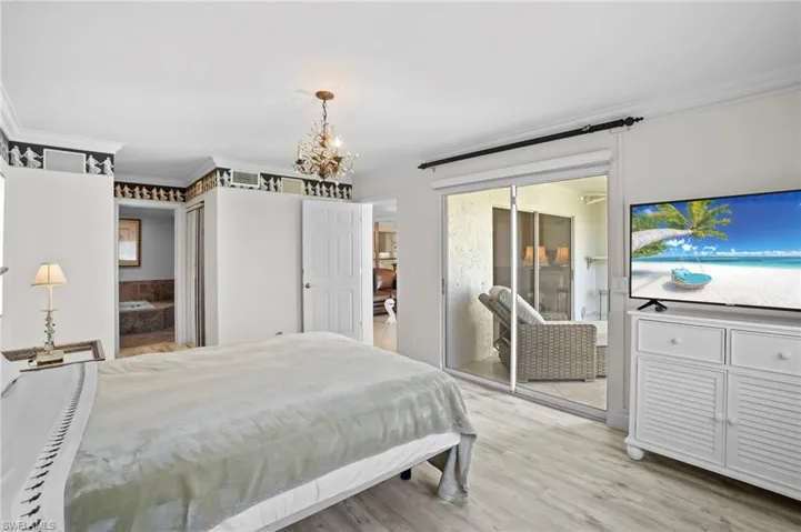 Bedroom with crown molding, access to exterior, light wood-style floors, and hanging lights