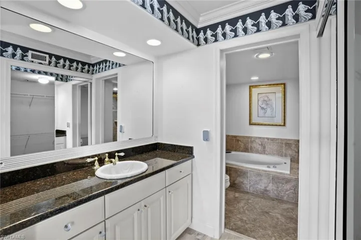 Full bathroom with recessed lighting, crown molding, vanity, a bath, and a walk in closet