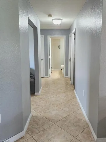 Hallway featuring a textured ceiling and light tile patterned flooring