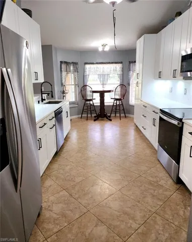Renovated Kitchen with appliances with stainless steel finishes, light tile patterned flooring, sink, and white cabinets
