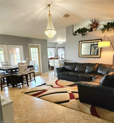 Tiled living room featuring lofted ceiling and a chandelier