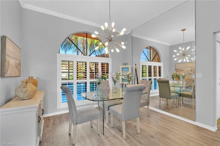 Dining room featuring ornamental molding, plenty of natural light, light wood-style floors, and a chandelier