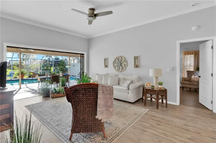 Living room with a sunroom, crown molding, wood finished floors, and a ceiling fan