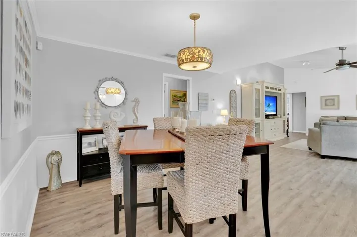Dining space featuring light wood finished floors, a ceiling fan, and crown molding