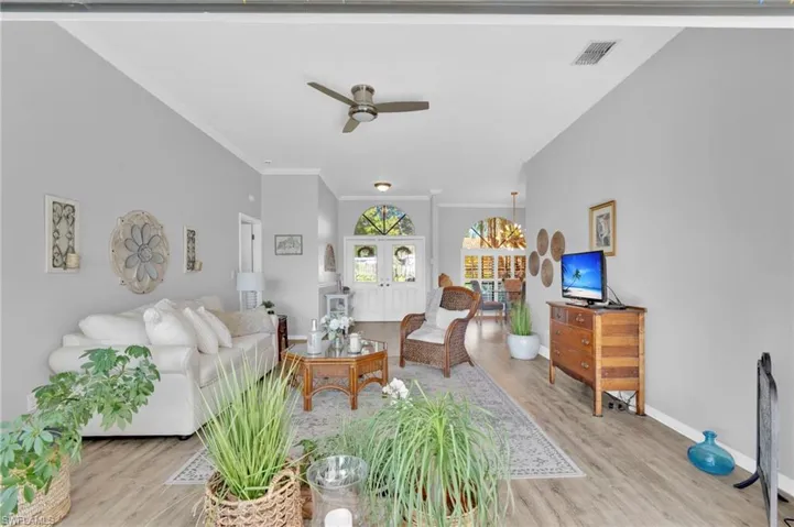 Living area with ceiling fan, ornamental molding, and light wood-style flooring