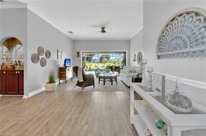 Living area featuring crown molding, light wood-type flooring, and a ceiling fan