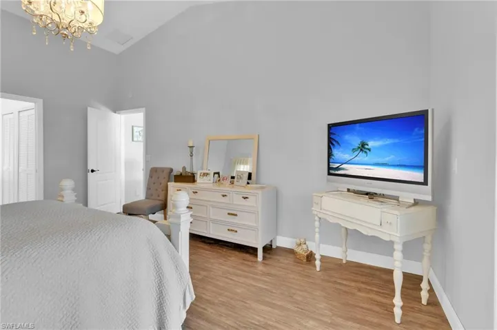 Bedroom featuring a chandelier, light wood-style flooring, and high vaulted ceiling