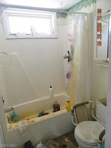 Full bathroom with shower / tub combo with curtain and toilet