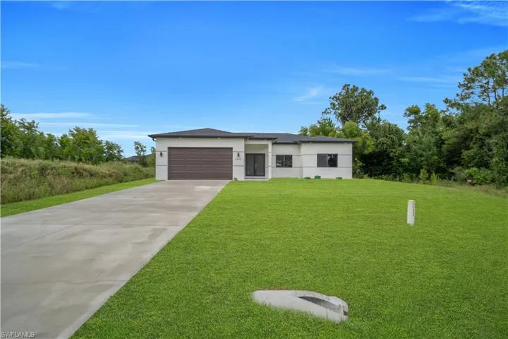 Contemporary single-story residence featuring a two-car garage, concrete driveway, and expansive lawn