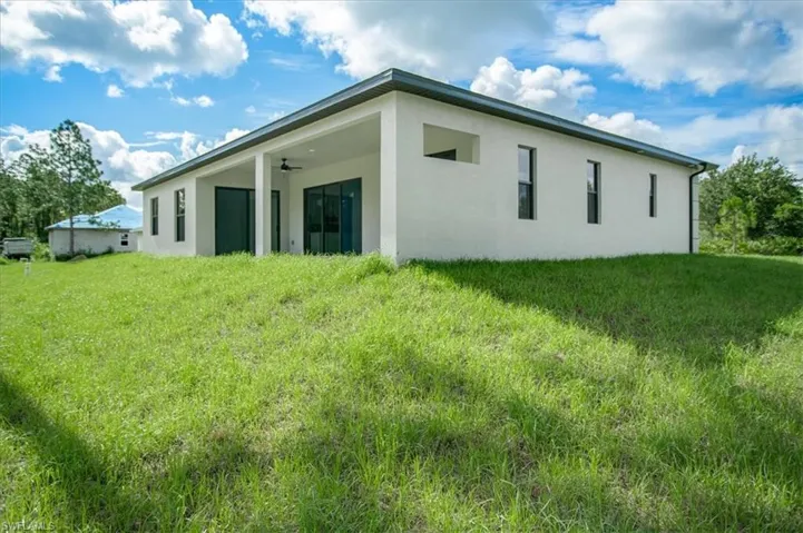 Rear view of house with a yard and ceiling fan