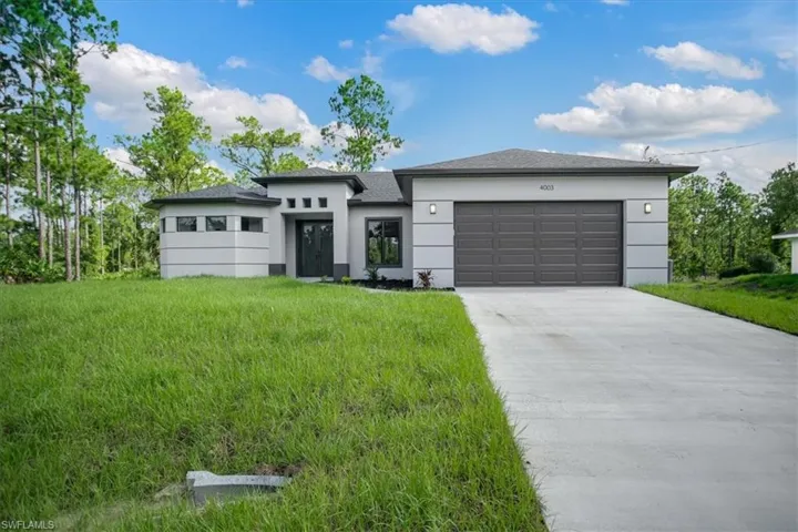 View of front of house with a garage and a front lawn