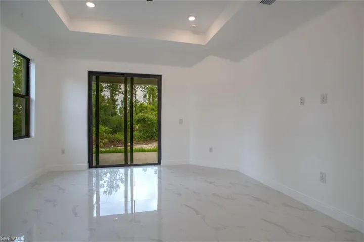 Empty room with light tile patterned flooring and a tray ceiling