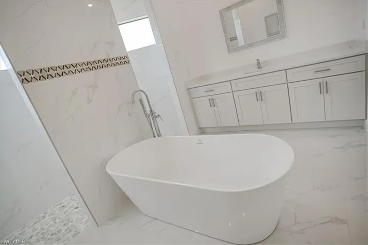 Bathroom with tile walls, tile floors, vanity, and a tub