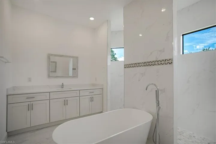 Bathroom featuring tile floors, a bath, and vanity
