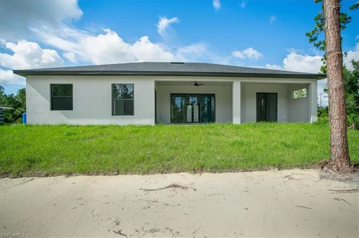 Rear view of house with ceiling fan and a lawn