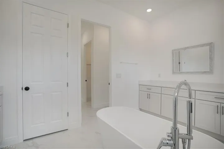Bathroom featuring a washtub, vanity, and tile flooring