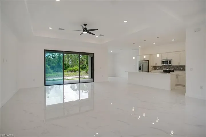 Unfurnished living room featuring light tile flooring and a tray ceiling