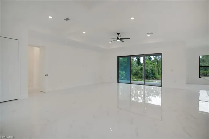 Tiled spare room featuring ceiling fan and a wealth of natural light