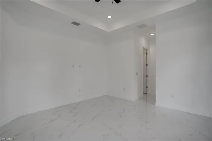 Unfurnished room with ceiling fan, light tile floors, and a raised ceiling