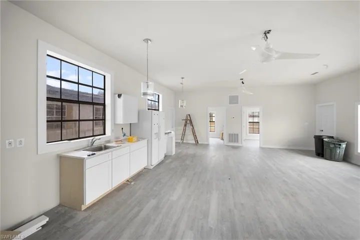 Kitchen with light countertops, white cabinetry, ceiling fan, light wood finished floors, and plenty of natural light