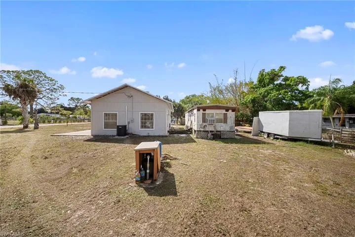 Rear view of house featuring a deck, a lawn, a gazebo, and an outbuilding