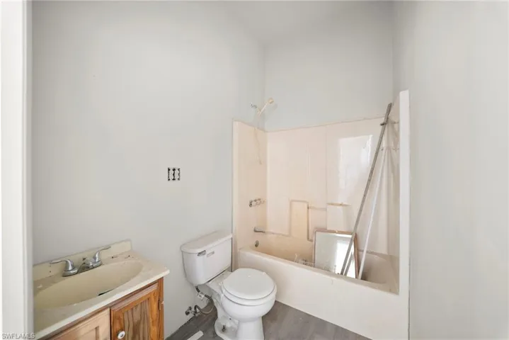 Bathroom featuring vanity, shower / bath combo with shower curtain, and dark wood finished floors