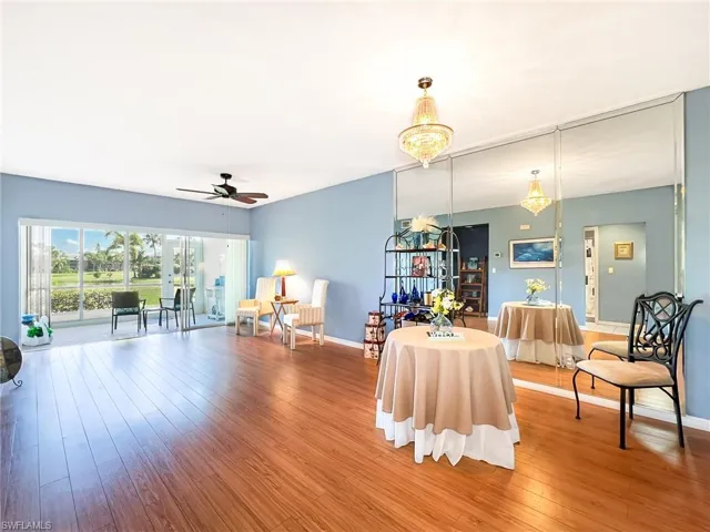 Living area featuring ceiling fan with notable chandelier and hardwood / wood-style floors