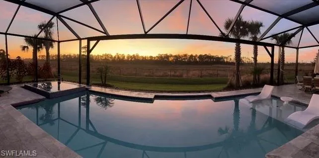 Pool at dusk with a lanai and a patio area