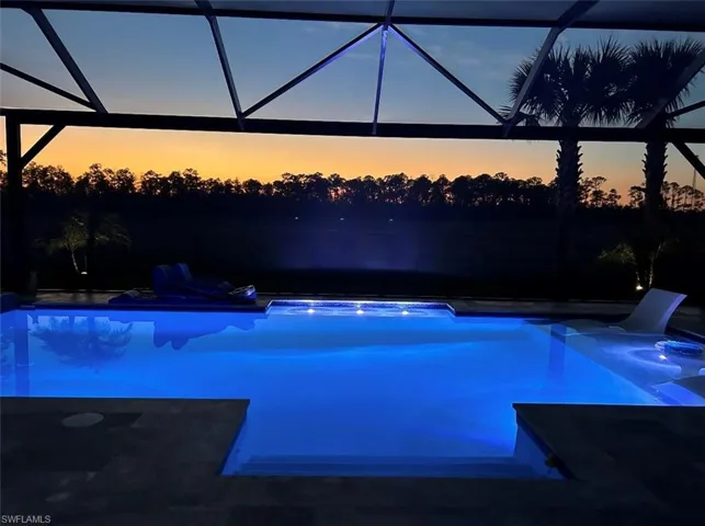 Pool at dusk featuring glass enclosure