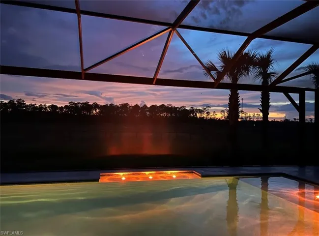 Pool at dusk featuring glass enclosure
