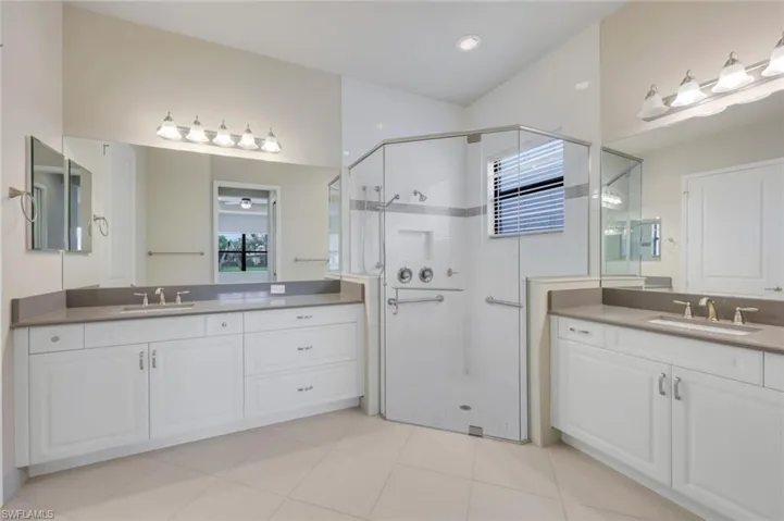 Master Bathroom with walk in shower, double vanities, white cabinetry and quartz counters