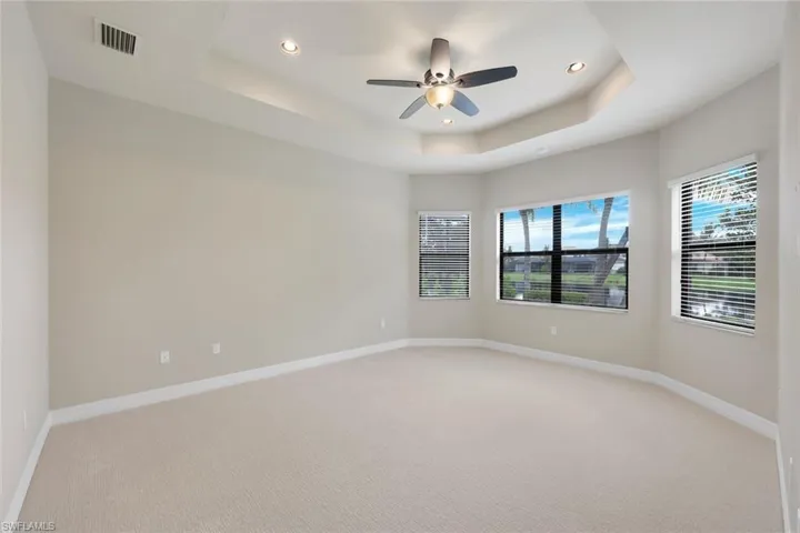 Master bedroom featuring a tray ceiling, ceiling fan, and new carpet