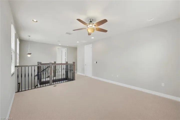 Newly Carpeted loft with ceiling fan and upgraded stair railing