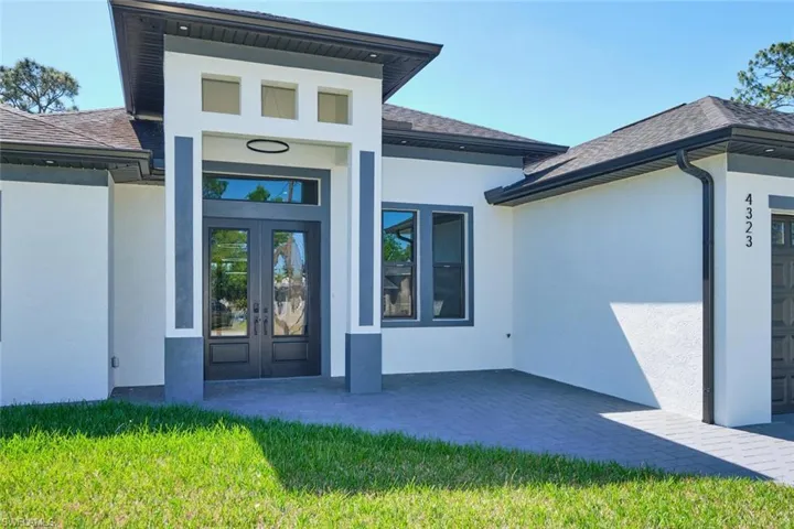 View of exterior entry featuring stucco siding, french doors, and roof with shingles