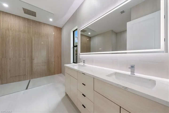 Full bathroom with double vanity, visible vents, walk in shower, and a sink