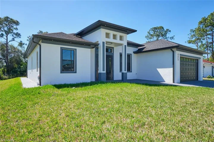 Prairie-style house with driveway, a shingled roof, stucco siding, a front lawn, and a garage