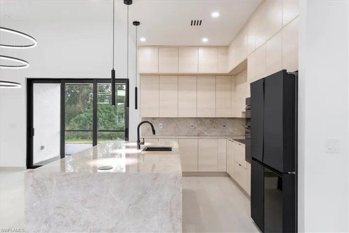 Kitchen featuring visible vents, decorative backsplash, freestanding refrigerator, a sink, and modern cabinets