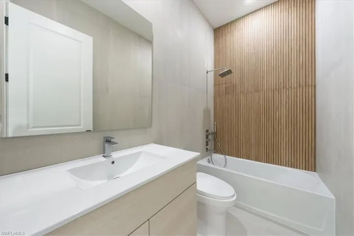 Bathroom with bathing tub / shower combination, toilet, and vanity