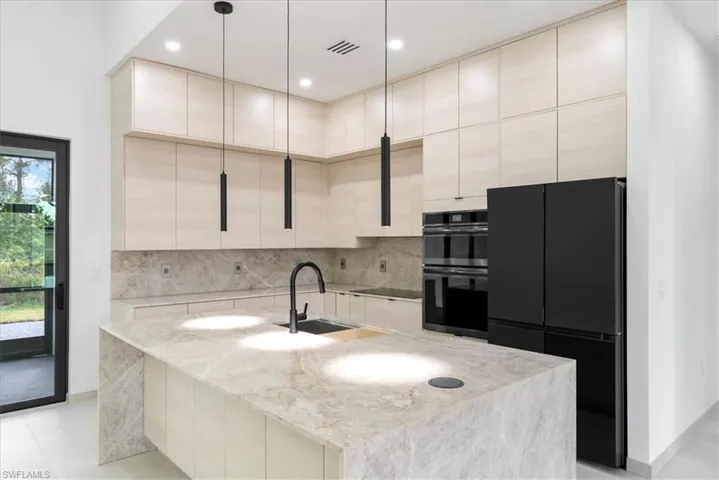 Kitchen with visible vents, modern cabinets, a sink, black appliances, and backsplash
