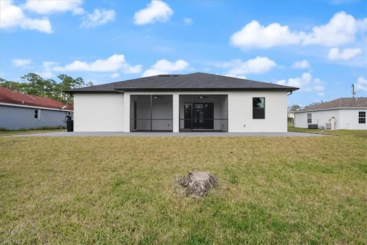 Rear view of property with central air condition unit, a lawn, a sunroom, and stucco siding