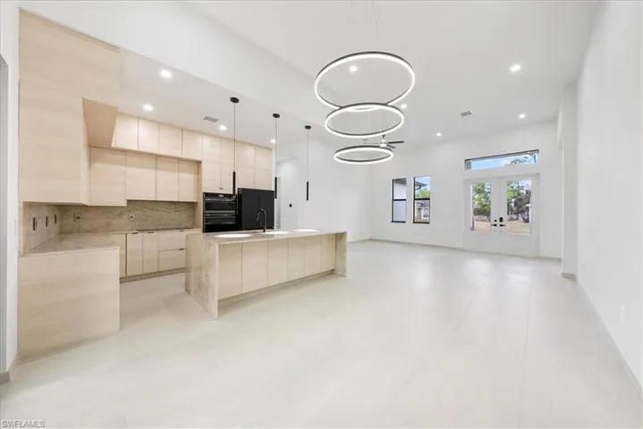 Kitchen with decorative backsplash, modern cabinets, light countertops, french doors, and light brown cabinets