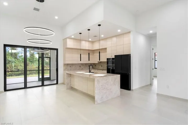 Kitchen with recessed lighting, dobule oven black, a sink, modern cabinets, and a large island with sink