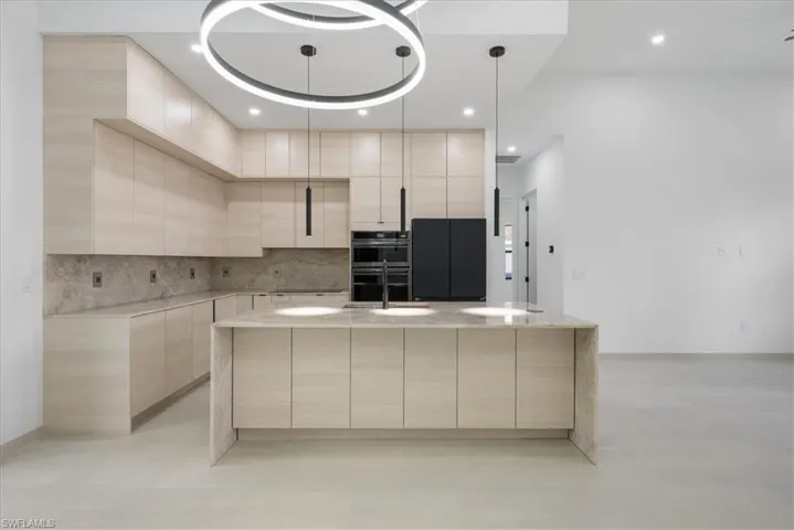 Kitchen featuring light brown cabinetry, stainless steel double oven, modern cabinets, and a sink
