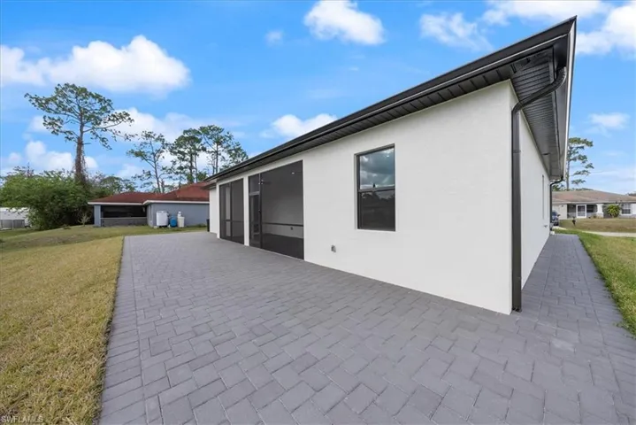 View of side of home featuring a patio, a lawn, and stucco siding