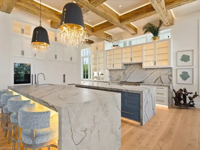 Kitchen with a breakfast bar area, light stone countertops, light wood-style floors, hanging light fixtures, and white cabinets