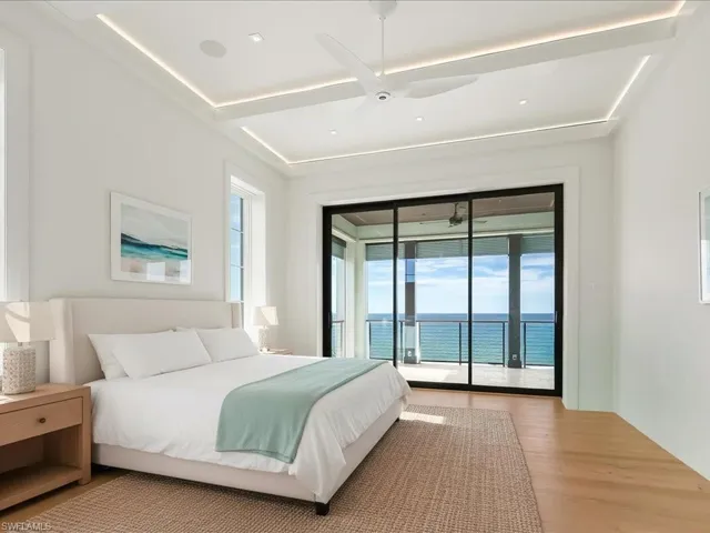Bedroom with a water view, access to outside, wood finished floors, and a ceiling fan