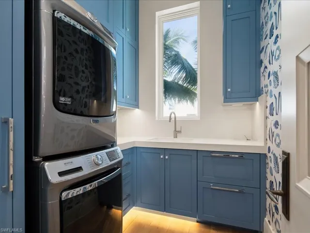 Laundry area featuring stacked washing machine and dryer and cabinet space