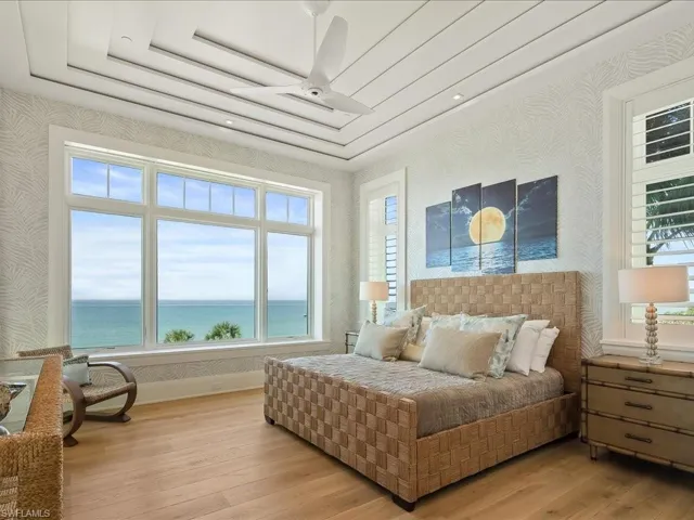 Bedroom with wallpapered walls, a water view, and hardwood / wood-style floors